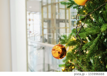Christmas tree decorated with ornaments and fairy lights in modern shopping mall 133996888