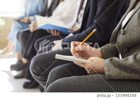 Business people sitting in a row working during a meeting or job conference making notes in notepad 133998168