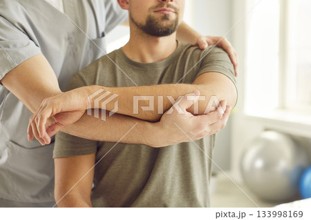 Chiropractor or physical therapist working with young man's arm in rehabilitation hospital. Chiropractor or physical therapist working with young man's arm in rehabilitation hospital. 133998169