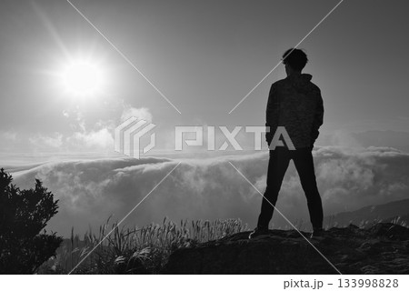 雲海を前に立つ男性のシルエットと朝日のモノクロ風景 133998828