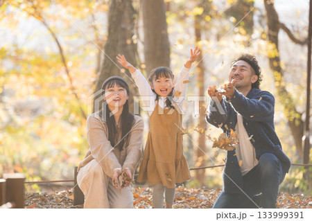 秋の公園で落ち葉遊びを楽しむ家族の笑顔・親子の幸せな秋の思い出ポートレート 133999391
