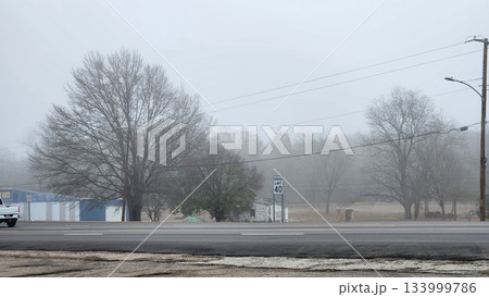 Foggy Street Scene With Power Lines, Trees, And Cars On A Quiet Road In Winter Dusk 133999786