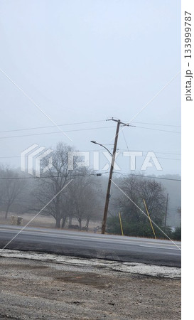 Foggy Street Scene With Power Lines, Trees, And Cars On A Quiet Road In Winter Dusk Foggy Street Scene With Power Lines, Trees, And Cars On A Quiet Road In Winter Dusk 133999787