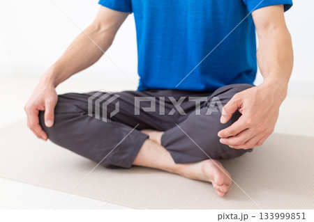 あぐらをかいて座るTシャツ姿のミドル男性 133999851