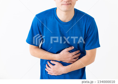 お腹の痛みに苦しむTシャツ姿のミドル男性 お腹の痛みに苦しむTシャツ姿のミドル男性 134000010