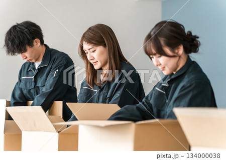 ダンボールに箱詰めする運送・物流・宅急便・宅配便・流通・配達・宅配業者の作業員の男女 134000038