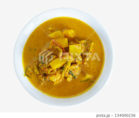 Thai pork curry with pineapple, served in a white bowl. This dish features a vibrant yellow-orange color, combining tender pork, sweet pineapple, and spices, the essence of traditional Thai cuisine 134000236