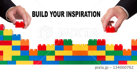 Hands building wall with colorful toys, displaying inspiration concept 134000762