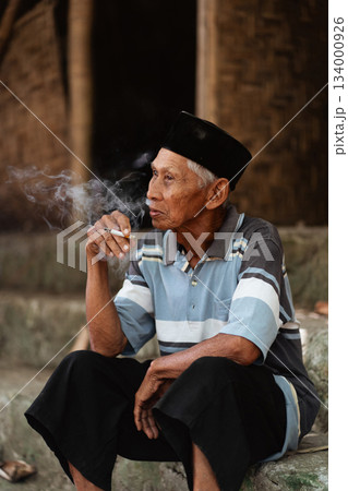 An Elderly Man Engaged in Smoking While Dressed in Traditional Cultural Attire 134000926