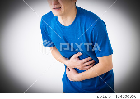 お腹の痛みに苦しむTシャツ姿のミドル男性 134000956