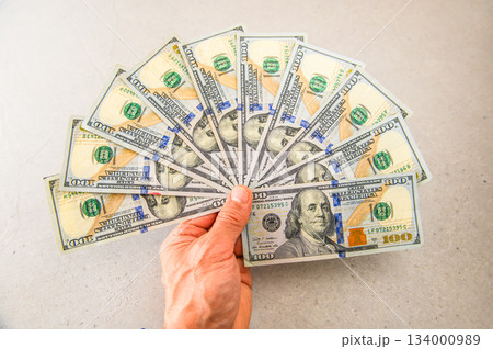 米100ドル紙幣10枚を扇状に広げ左手で差し出すクッキリピント 134000989