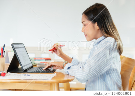 businesswoman working on laptop and writing in diary businesswoman working on laptop and writing in diary 134001901
