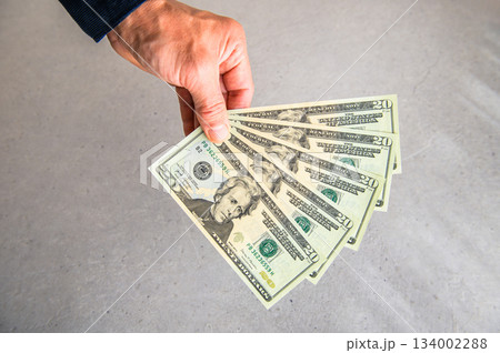 米20ドル紙幣5枚を左手で扇状に広げ奥から手前に差し出すアングルショット 134002288