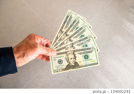 米20ドル紙幣5枚を左手で扇状に広げ左側から差し出すアングルショット 134002291