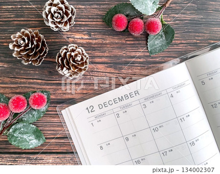 木製テーブルに置かれた12月のスケジュール帳とクリスマスオーナメント 134002307