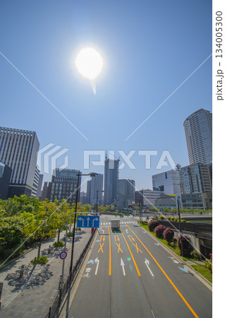 太陽の光が差し込む大通りと高層ビル群の広角風景 134005300