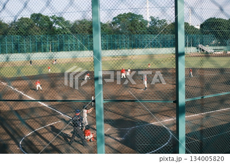 金網越しに見る土のグラウンドと青春の野球試合 134005820