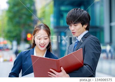 オフィス街でファイルを見るビジネスマンとビジネスウーマン 134006575