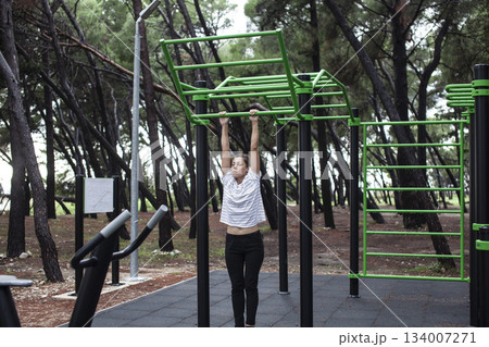 young pretty brunette woman outside making sport exercises on training playground, lifestyle people concept young pretty brunette woman outside making sport exercises on training playground, lifestyle people concept 134007271