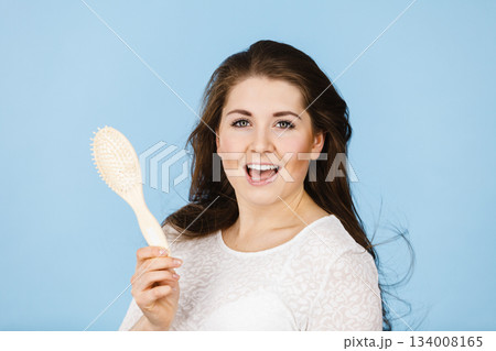 Happy woman brushing her hair Happy woman brushing her hair 134008165