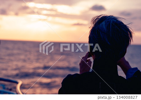 夕日を撮影するシニア男性の背中シーン 夕日を撮影するシニア男性の背中シーン 134008827