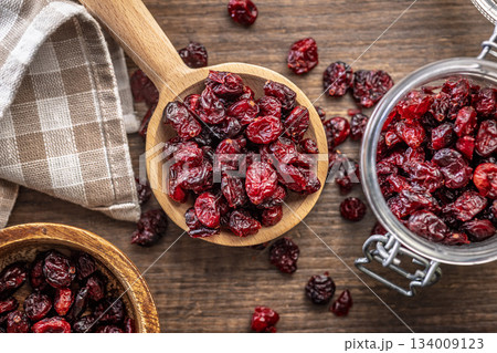Tasty dried cranberries on wooden spoon on wooden table. Top view. Tasty dried cranberries on wooden spoon on wooden table. Top view. 134009123