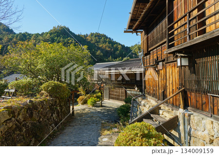 石畳の小路と木造町家が並ぶ妻籠宿の静かな町並みと山あいの風景 134009159