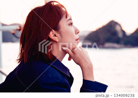 夕景の海を見つめる20代女性の後ろ姿 夕景の海を見つめる20代女性の後ろ姿 134009238