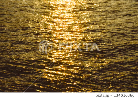 Reflection of golden sunlight on water. Sunset sea view with sparkle sunlight. Sunset light hitting on the ocean. Sunset sea background. 134010366