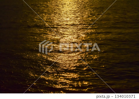 Reflection of golden sunlight on water. Sunset sea view with sparkle sunlight. Sunset light hitting on the ocean. Sunset sea background. Reflection of golden sunlight on water. Sunset sea view with sparkle sunlight. Sunset light hitting on the ocean. Sunset sea background. 134010371