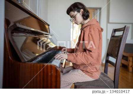 Concentrated on playing classical music on piano, pianist girl touch keys, practicing skills at home Concentrated on playing classical music on piano, pianist girl touch keys, practicing skills at home 134010417