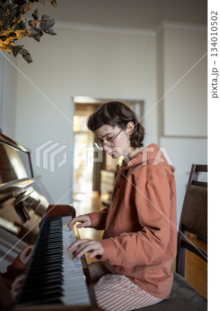 Girl student pianist practicing music skills playing piano at home, pumps up your piano skills 134010502