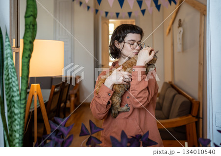 Woman adapting homeless pet cat petting holding in hands at home. Cat therapy 134010540