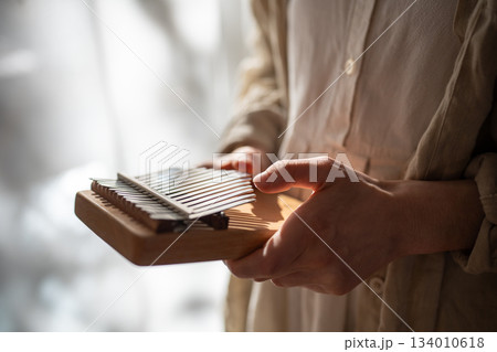 Kalimba ethnic musical instrument. Hands playing relaxation melody on metal keys, producing sounds. 134010618