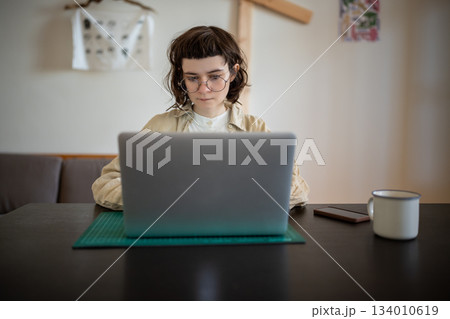 Concentrated teenager working, studying with laptop computer in comfortable conditions at home  134010619