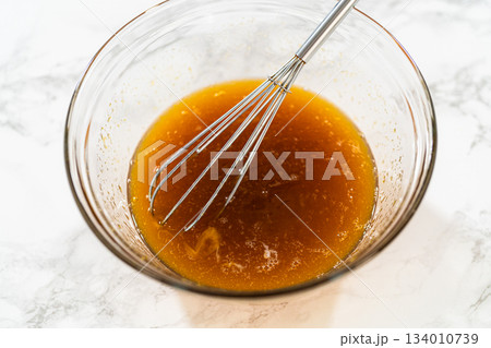 Two large eggs cracked into a glass bowl, combined with molasses. This mixture adds richness, moisture, and depth of flavor to the Classic Red Gingerbread Dough. 134010739