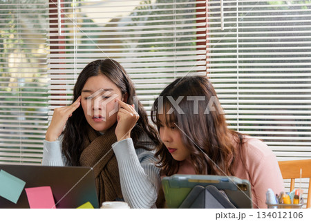 Young busy people meet office, team consult financial work project, one businesswoman looks stressed and rubs temples, while colleague intently studies tablet for business solution, dedicated work. 134012106