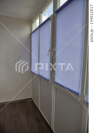 Modern enclosed balcony interior with roller blinds. 134012617