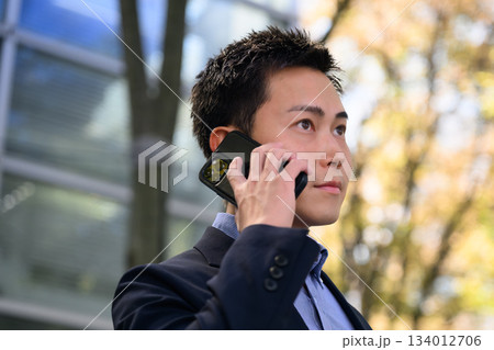 携帯で話す営業マン 134012706