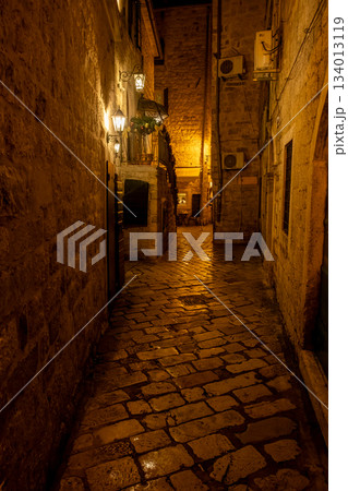Old town alley with warm electric lantern light in Kotor 134013119
