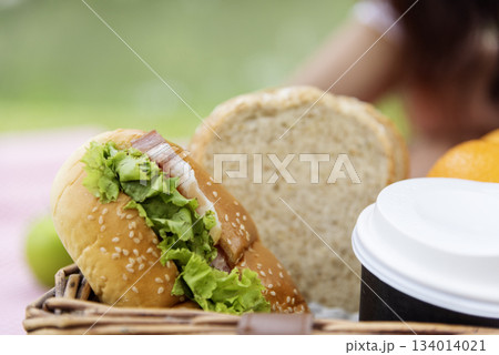 Picnic basket food bread fresh fruit coffee cup orange juice in wood wicker box on red Blanket. Wheat bakery fruit food and drinks in green park outdoor lifestyle. Breakfast healthy appetizer box. Picnic basket food bread fresh fruit coffee cup orange juice in wood wicker box on red Blanket. Wheat bakery fruit food and drinks in green park outdoor lifestyle. Breakfast healthy appetizer box. 134014021