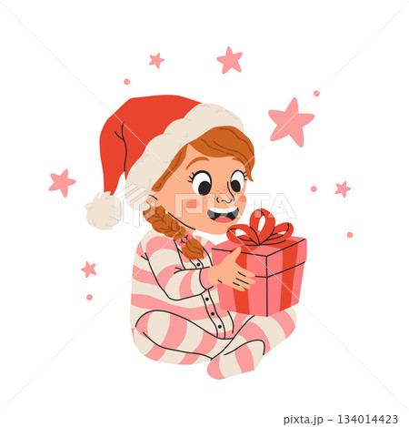 Vector illustration of cartoon happy little girl smiling, sitting in striped pajamas and red santa hat holding present with a bow for christmas. 134014423