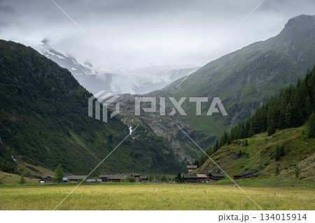 Picturesque alpine village nested in a valley with massive glacier above it, Austrian Alps Picturesque alpine village nested in a valley with massive glacier above it, Austrian Alps 134015914