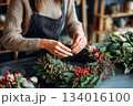 Creating a beautiful holiday wreath with natural materials in a cozy workshop decorated for the festive season 134016100
