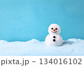 Cute snowman with a cheerful smile stands on soft snow against a bright blue background during winter 134016102