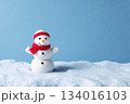 Snowman stands cheerfully in a snowy landscape with blue background, showcasing winter spirit and joy during holiday season in daylight 134016103