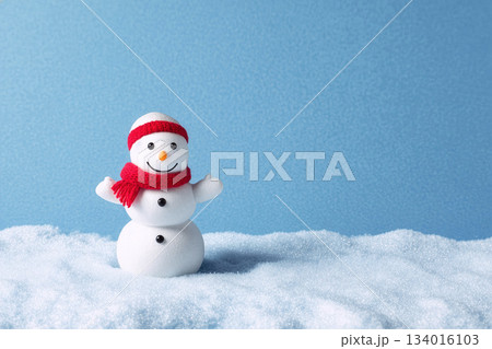 Snowman stands cheerfully in a snowy landscape with blue background, showcasing winter spirit and joy during holiday season in daylight 134016103