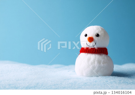 Colorful snowman sitting cheerfully in a snow-covered landscape against a bright blue background during a winter day 134016104