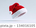 Bright red Christmas hat with white fluffy trim floating against a simple gray background, evoking holiday spirit and festive excitement during the winter season 134016105