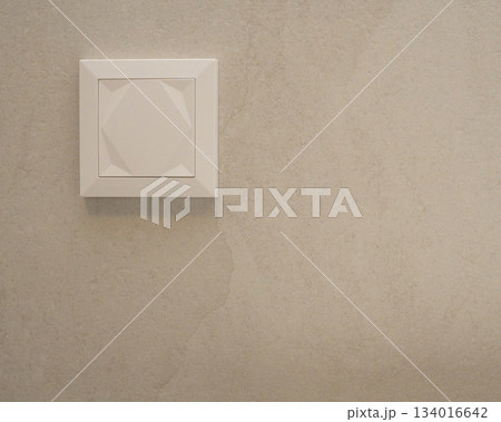 Close-up view of a modern white wall switch installed on a smooth beige wall. Minimalistic and neutral design fits themes of interior details, home renovation, electrical components, and contemporary Close-up view of a modern white wall switch installed on a smooth beige wall. Minimalistic and neutral design fits themes of interior details, home renovation, electrical components, and contemporary 134016642